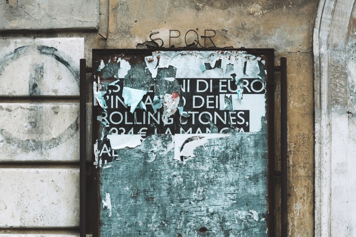 Verwittertes Plakat mit teilweise abgerissenen Texten an einer alten Wand