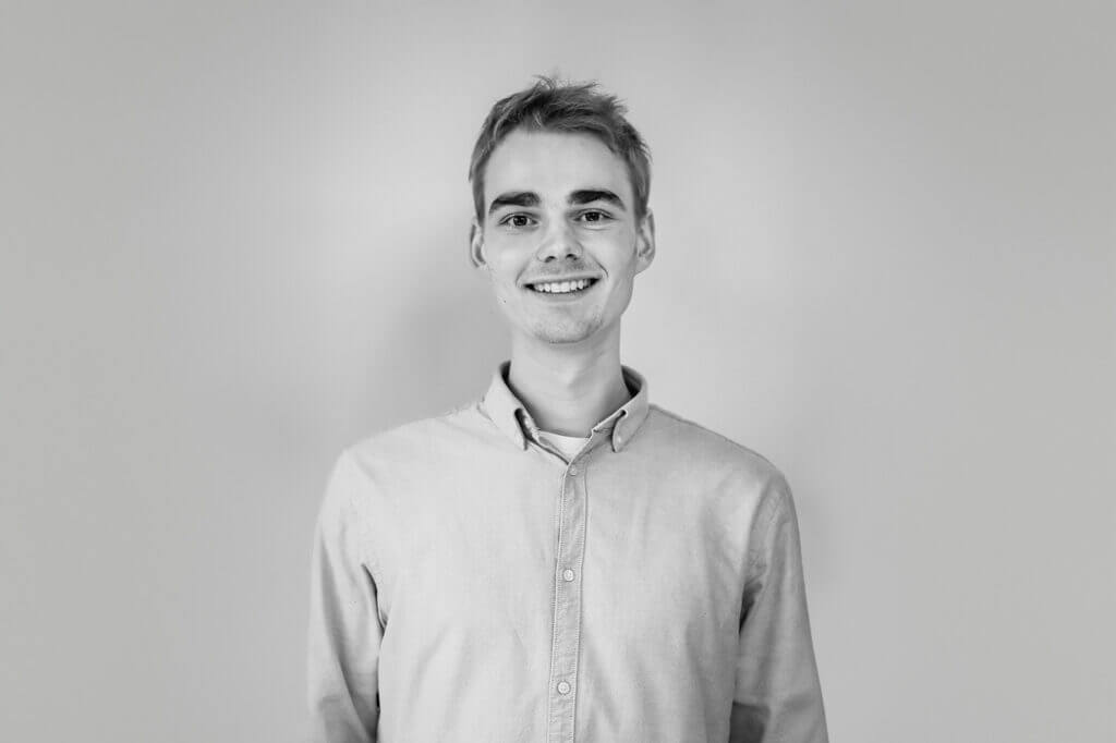 Porträt eines lächelnden Mannes in einem Hemd vor einem hellen Hintergrund