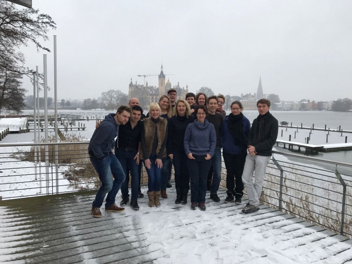 Gruppe von Personen im Schnee vor einem See mit Schloss im Hintergrund