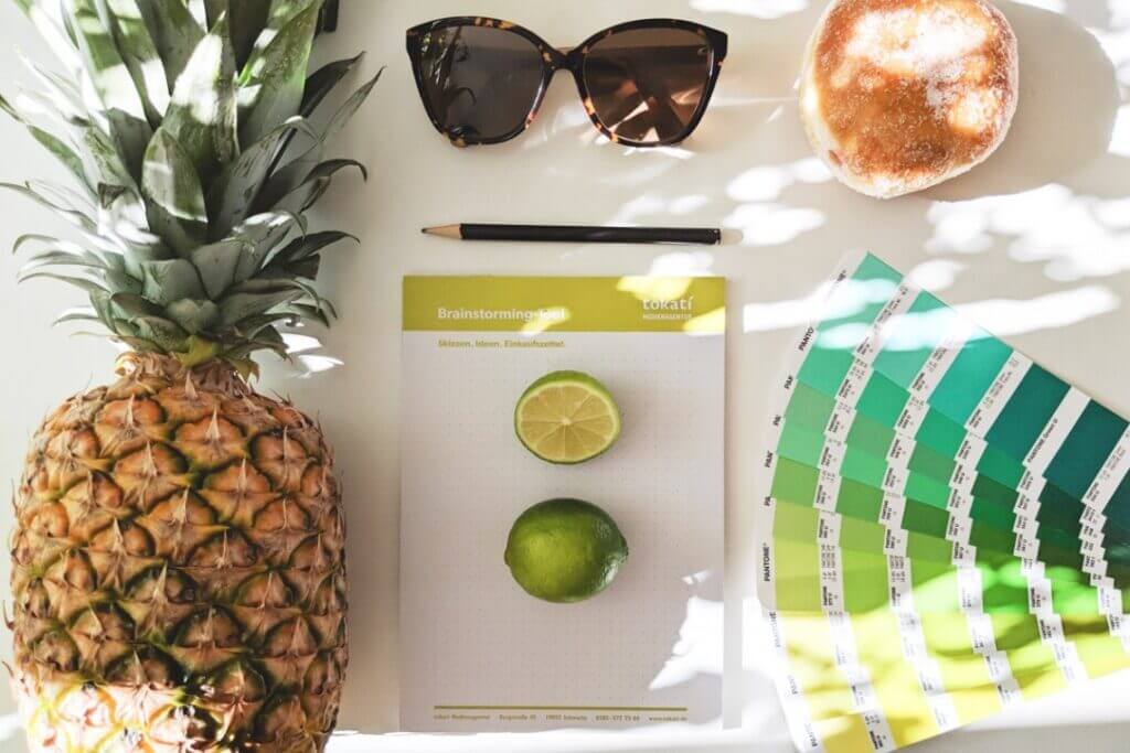Ansammlung an Sommer-essentials:
Ananas, Limetten, Stift, Sonnenbrille, die aktuellen Trendfarben und der tokati Brainstorming Block