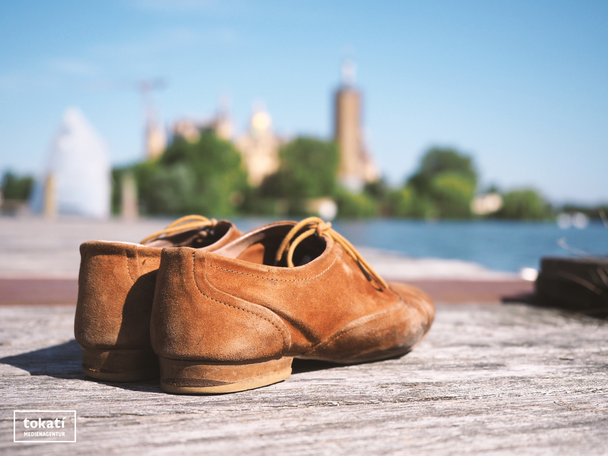 Braune Lederschuhe auf einem Steg mit Schloss im Hintergrund